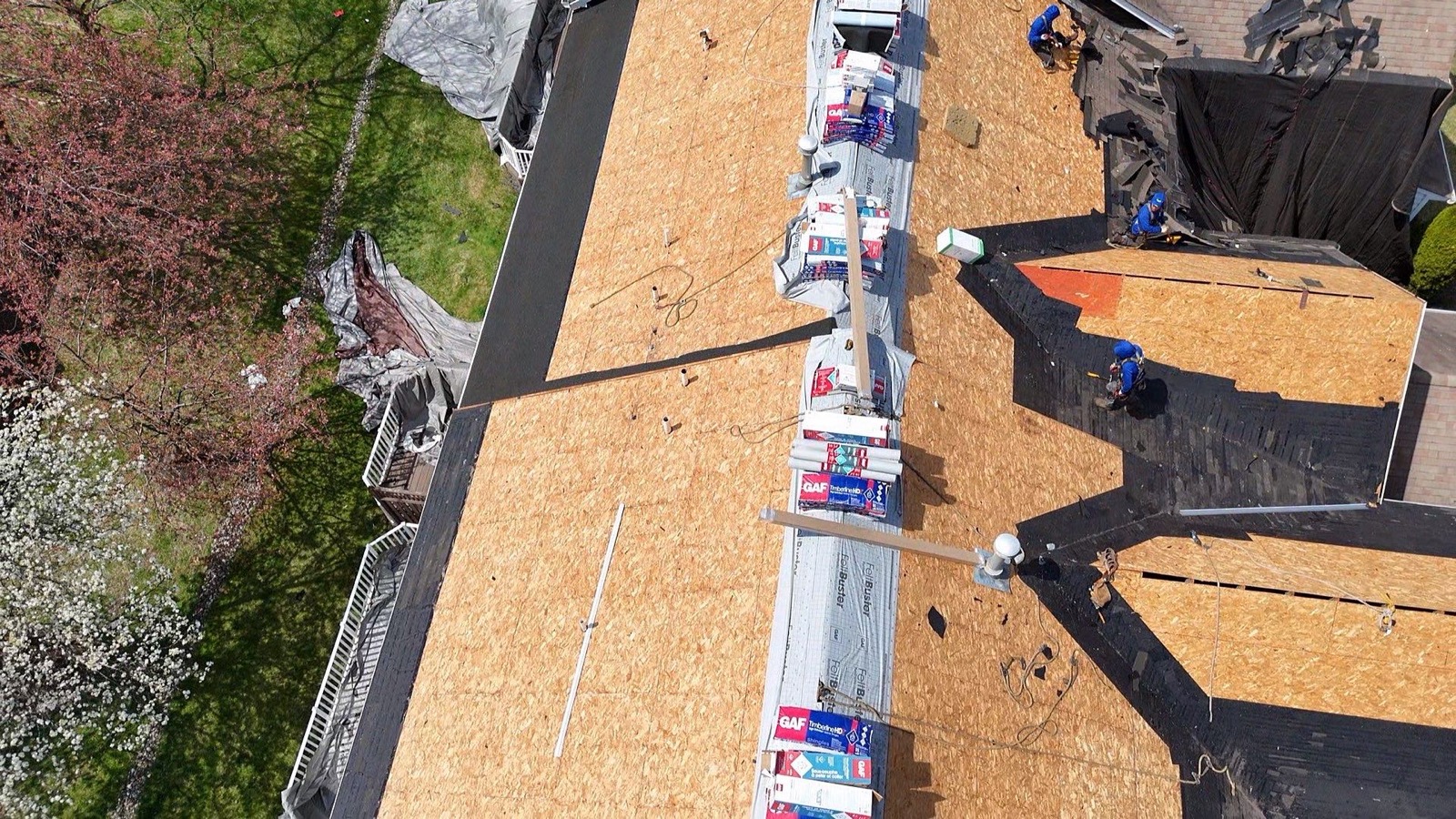 GAF bundles and FeltBuster lined up along a suburban roof ridge