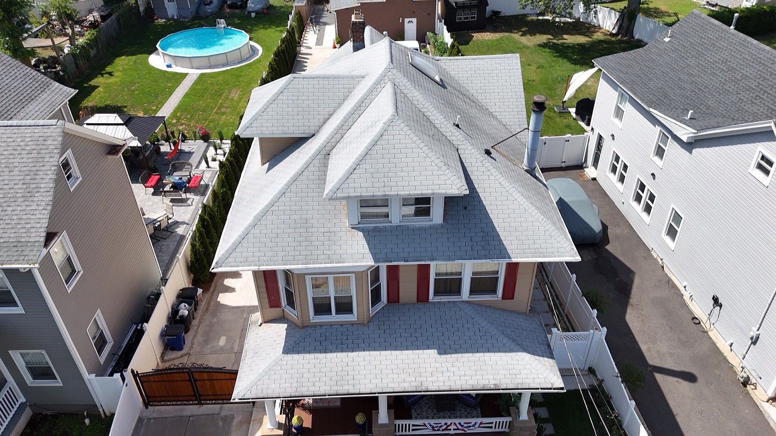 Completed tan shingle roof on a Victorian home with red shutters